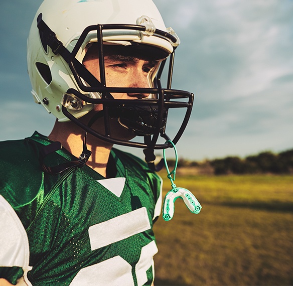 Teen with mouthguard hanging from football helmet