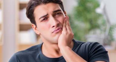 Man with toothache holding cheek in pain