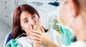 Fearful woman in need of sedation dentistry covering her mouth