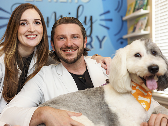 Dentist smiling and hugging a dog
