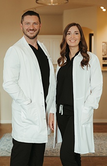 Two dentists smiling in a hallway