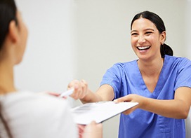 Team member handing patient dental insurance form