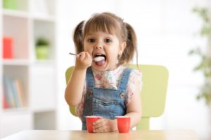 cute young girl eating yogurt  