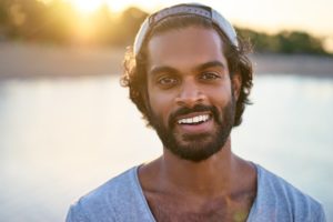 young man smiling in front of river 