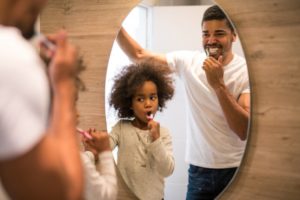 father and young daughter brushing teeth 