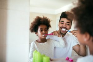 father and young daughter brushing together 