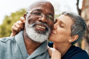 smiling older man being kissed on the cheek by wife 