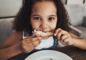 little girl eating a piece of chicken 